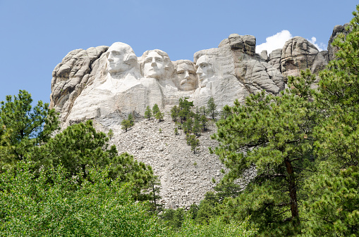 The four America's presidents, Thomas Jefferson, Abraham Lincoln, Theodore Roosevelt and George Washington, carved into the mountain at Mount Rushmore National Monument, showing the scree slope from the removed rock.
