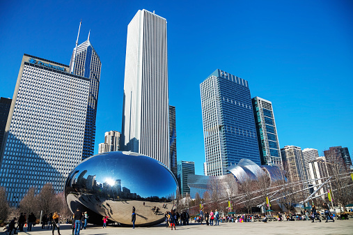Сhicago, USA - April 9, 2014: Cloud Gate sculpture with tourists in Millenium park in Chicago, IL. This public sculpture is the centerpiece of the AT&T Plaza in Millennium Park within the Loop community area.