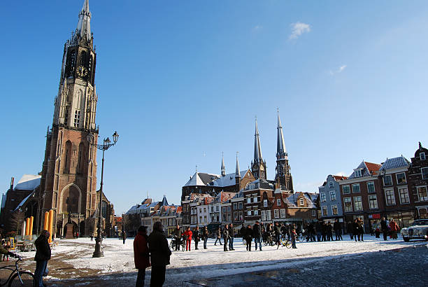 snowy main square in Netherlands with people, blue sky Delft, Netherlands - January 31, 2010: snowy main square of delft in the Netherlands in the morning with people and blue sky as lifestyle delft winter netherlands snow stock pictures, royalty-free photos & images