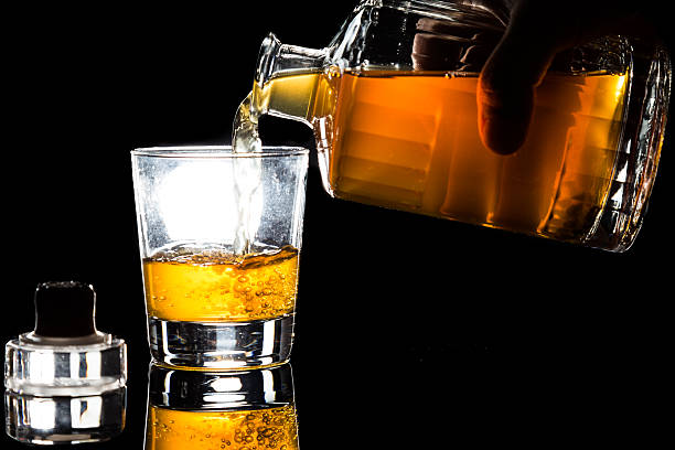 istock Hand pouring whiskey into glass against dark background 465843078