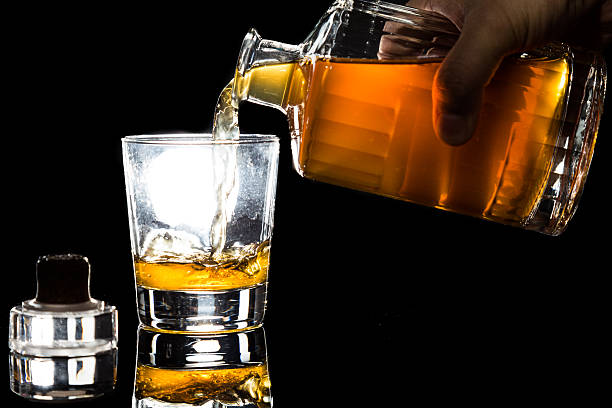 istock Hand pouring whiskey into glass against dark background 465843080