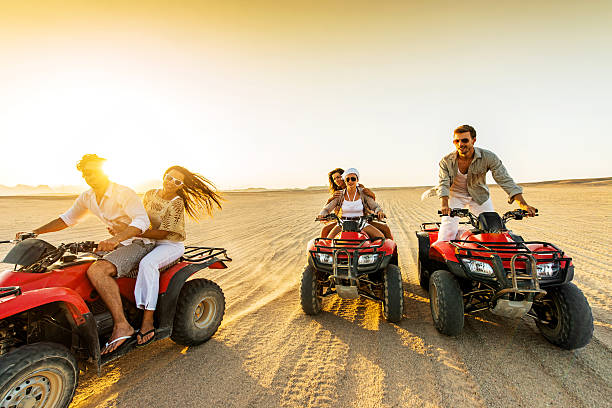 istock Young adults riding red ATVs in a desert at sunset 465843524