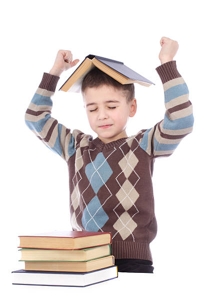 istock Smiling young boy with a book on his head 465843555