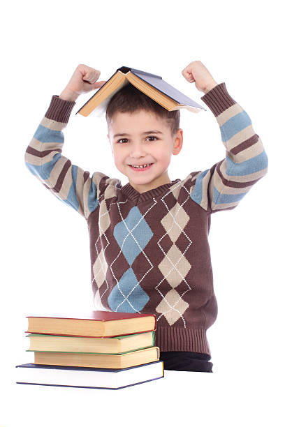 istock Smiling young boy with a book on his head 465843615