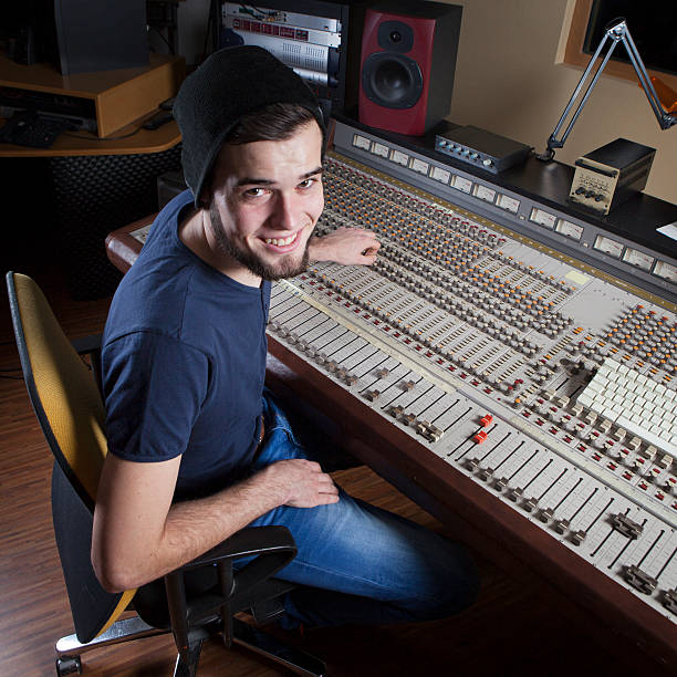 Male sound engineer using a studio mixing desk Male sound engineer using a studio mixing desk sound technician stock pictures, royalty-free photos & images