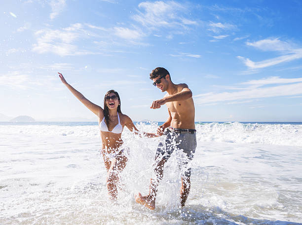 istock A couple wearing sunglasses splashing in ocean 465845054