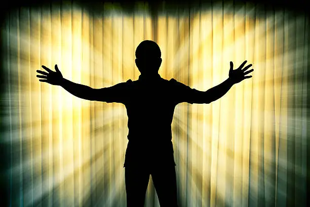 Silhouette of man surrendering with two hands raised in air