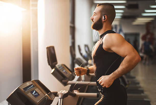 vue latérale d'une jeune athlète courir sur un tapis de course. - treadmill photos et images de collection