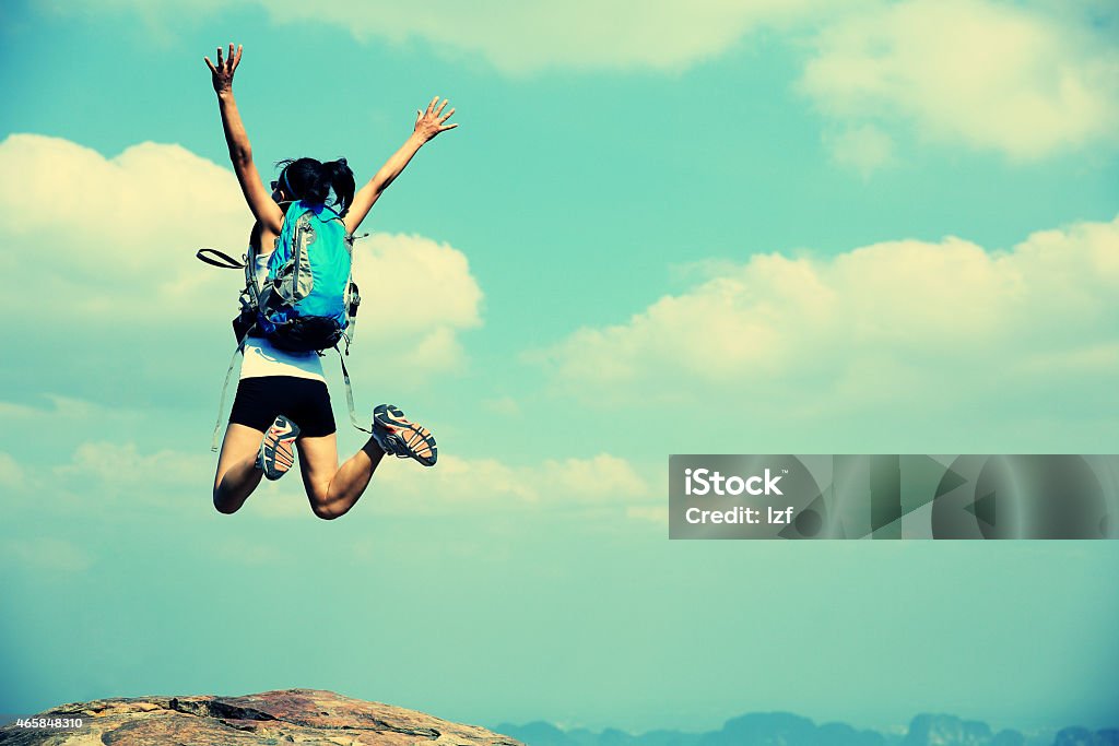 cheering woman hiker jumping on mountain peak Retro Style Stock Photo