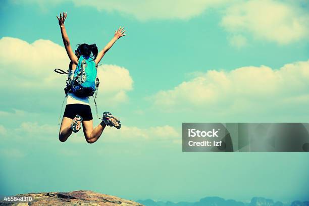 Cheering Woman Hiker Jumping On Mountain Peak Stock Photo - Download Image Now - Retro Style, Hiking, Jumping