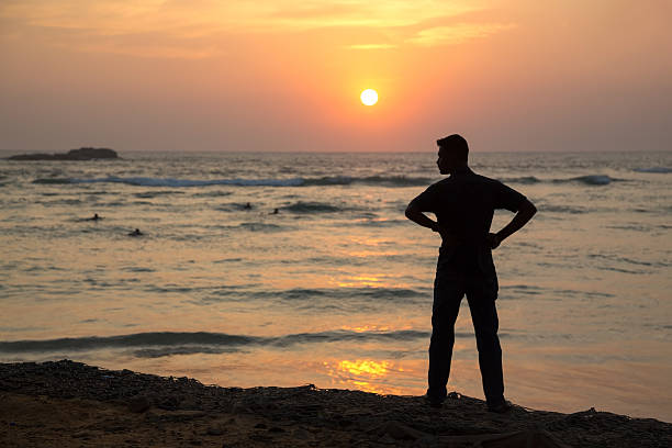 istock Silhouette  of a man standing on sandy beach at sunset. 465860454