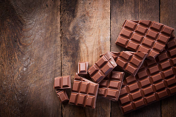 Chocolate on Rustic Wood An arrangement of broken milk chocolate blocks, shot overhead on a rustic worn wooden background, using natural daylight.  milk chocolate stock pictures, royalty-free photos & images