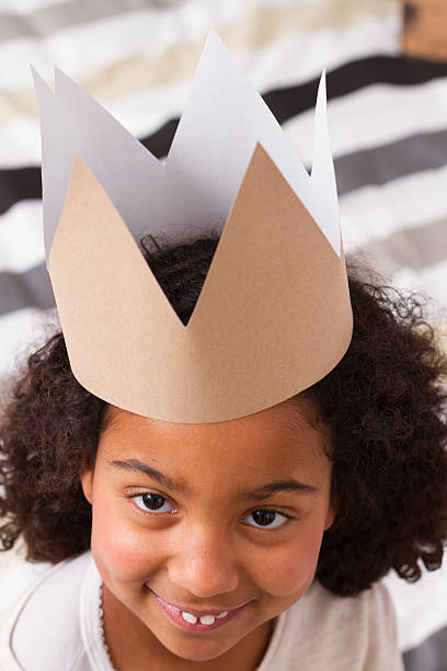 istock Child girl with paper crown looking at camera 465870188