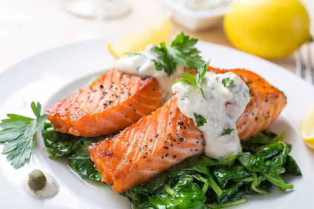 Grilled Salmon on a Bed of Spinach, Cream Sauce and Lemon Wedges