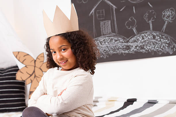 istock Child girl with paper crown looking at camera 465878314