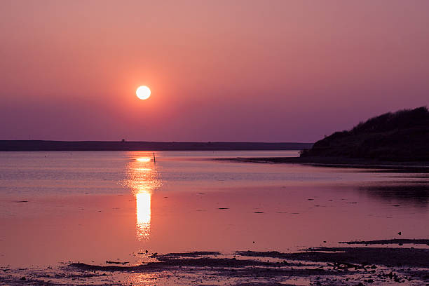 The sun goes down over the East Fleet in Dorset Red sky is reflected in the brackish waters of the Fleet near Portland studland heath stock pictures, royalty-free photos & images