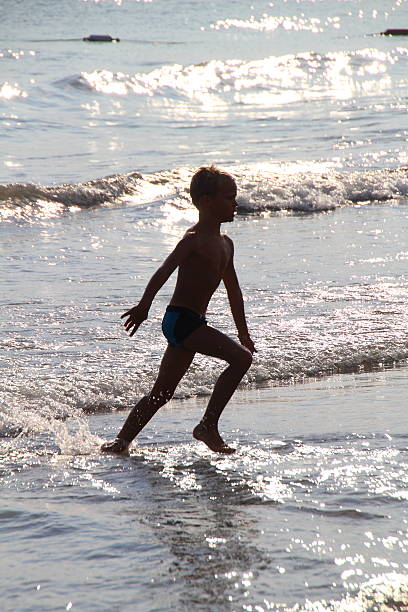 istock young boy walking in the sea 465884592