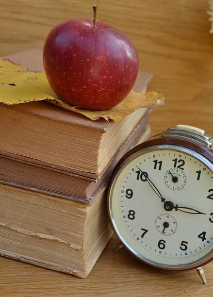 istock Vintage books with old clock and red apple 465884803