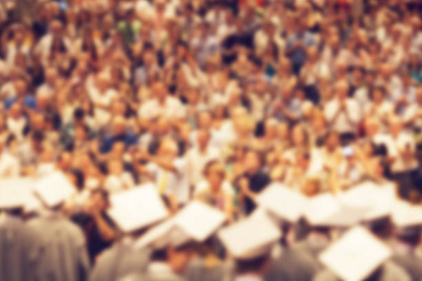 Audience in a big concert hall during graduation ceremony. Defocusing gaussian blur filter applied, with vintage instagram look.