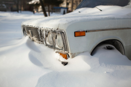 White old car covered with snow after the winter blizzard