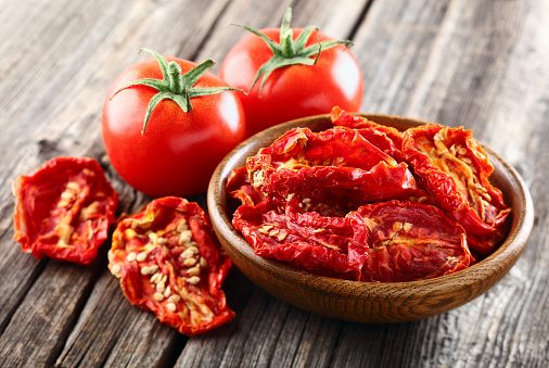 Fresh and dried tomato on a wooden background