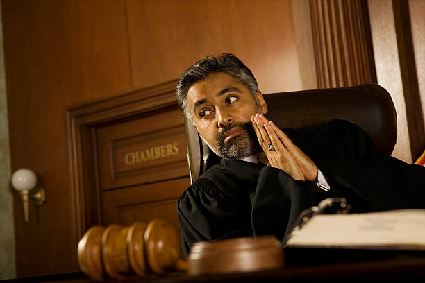 istock Judge With Hands Clasped Looking Away In Court Room 465912202