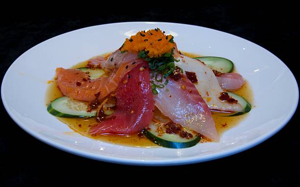 Sashimi Appetizer This is a closeup of a Sashimi Appetizer which is made with; salmon, tuna, kampachi, white tuna, red snapper, striped bass, cucumber, flying fish roe, carrots, scallions, chili oil, ponzu sauce, chili peppers. salmon and red snapper stock pictures, royalty-free photos & images