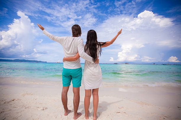 istock Back view of young couple on white beach 465912770