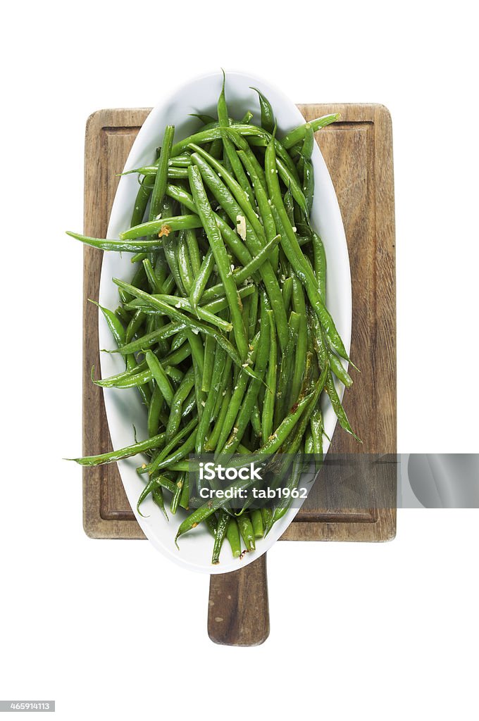 Freshly Cooked Green Beans isolated on White Vertical photo of freshly cooked green beans in white bowl on black walnut serving board isolated on white Agriculture Stock Photo
