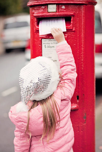 istock Little Girl Posting a Letter in British Mailbox 465920125
