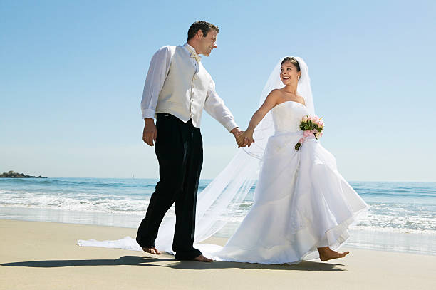 istock Newlywed Couple Holding Hands While Walking On Beach 465921497