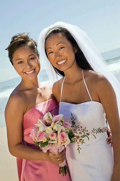 Bride And Bridesmaid With Flower Bouquet Smiling On Beach