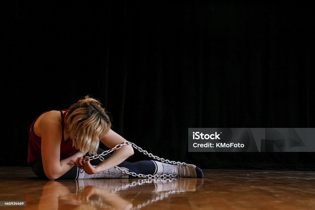 In Chains Woman sitting on the ground tangled in chains Adult Stock Photo