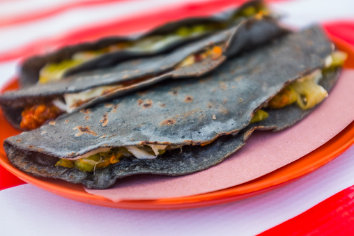 Picture of a delicious quesadilla prepared with manchego cheese, squash blossom, and blue corn tortilla.