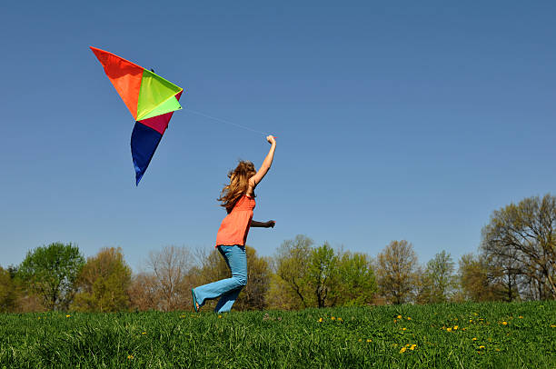 istock Young girl running with kite 465940185