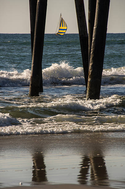 istock yellow and blue sailboat through pier pilings 465957793