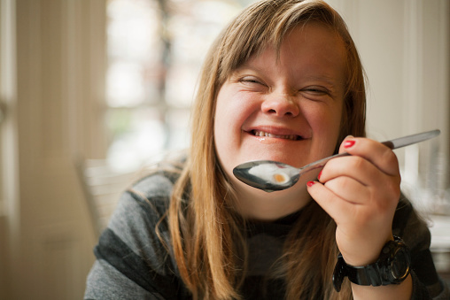 Portrait of girl with down syndrome eating.