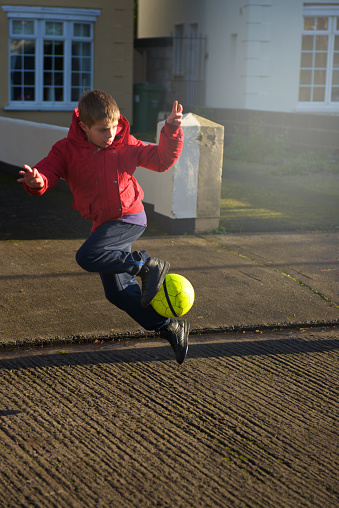 kid soccer player free style evolution in the street with fluorescent ball