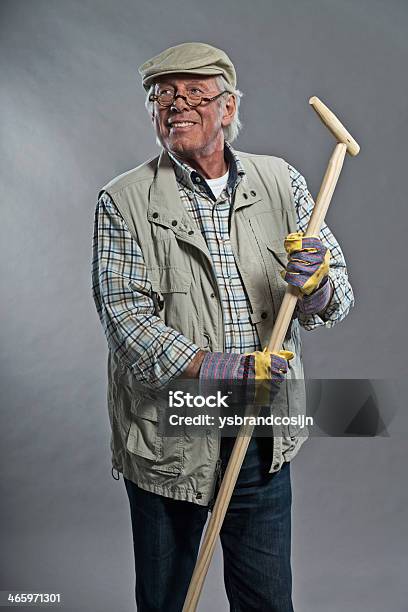 Photo libre de droit de Jardinier Homme Senior Souriant Avec Un Chapeau Tenant Pioche Portant Des Lunettes banque d'images et plus d'images libres de droit de Adulte