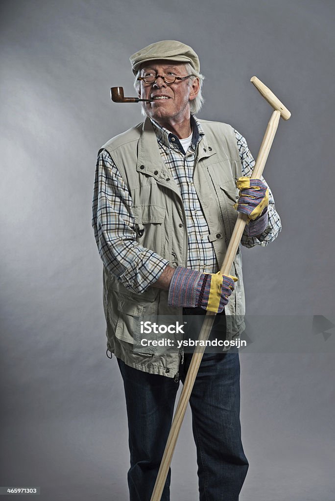 Jardinier homme senior avec chapeau tenant pioche.  Portant des lunettes. - Photo de Adulte libre de droits