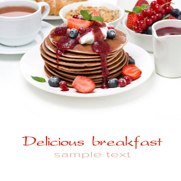 stack of pancakes with cream, fruit sauce and berries