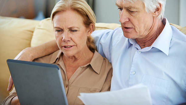 Staying informed online Shot of an elderly couple going over their paperwork with the help of a digital tablet informed stock pictures, royalty-free photos & images