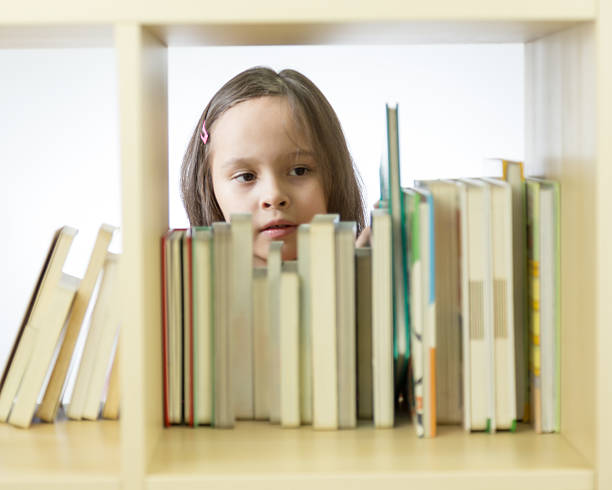 istock Young girl looking at books on bookshelf 465993642