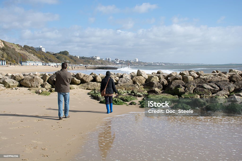 Couple approaching the rocks at the beach A couple approach the rocks at the beach 2015 Stock Photo