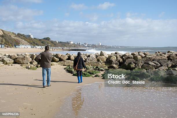 Couple Approaching The Rocks At The Beach Stock Photo - Download Image Now - 2015, 60-64 Years, 65-69 Years