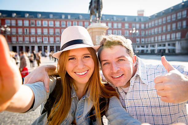 friends tourist couple visiting Spain on holidays taking selfie picture young beautiful friends tourist couple visiting Spain in holidays exchange students and taking selfie stick picture together in town happy on sunny day in travel and vacation concept selfie madrid photos stock pictures, royalty-free photos & images