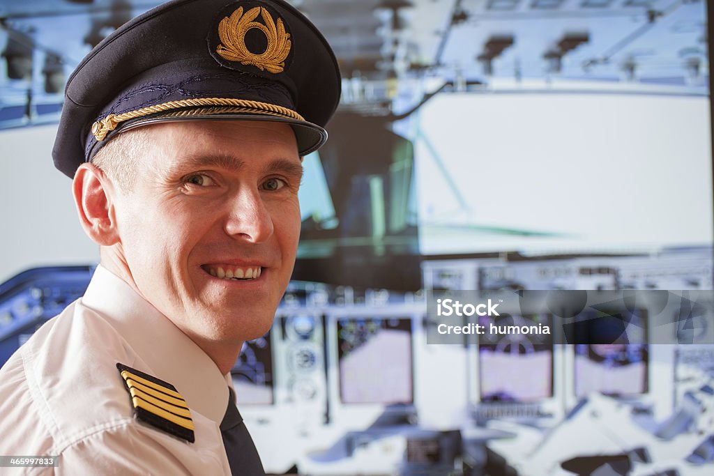Airline pilot Pilot captain  wearing uniform with epauletes, hat with golden wings sitting inside airliner with visible cockpit during flight. Adult Stock Photo