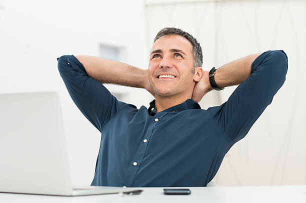 Relaxed Man Daydreaming Mature Man Satisfied Sitting In Front Of Laptop Daydreaming bending over backwards stock pictures, royalty-free photos & images