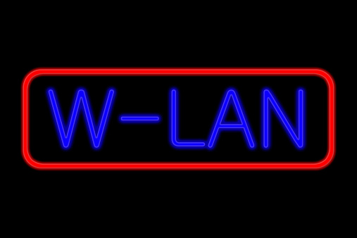 Illuminated Neon sign with blue Letters and red frame showing w-lan isolated on black background
