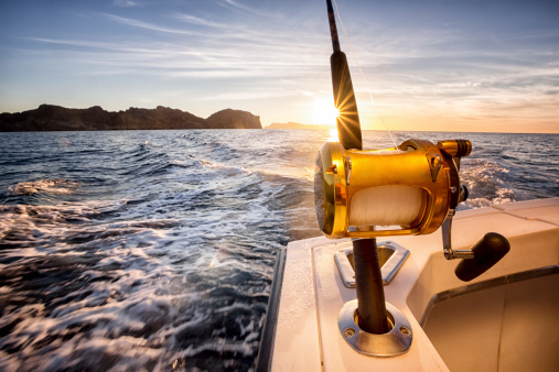 Big fishing reels on a boat in the ocean.  These reels are used to catch big game fish such as Mahi-mahi, dorado, tuna, sailfish, swordfish sharks and marlin.  They are used in tropical and cold water oceans.